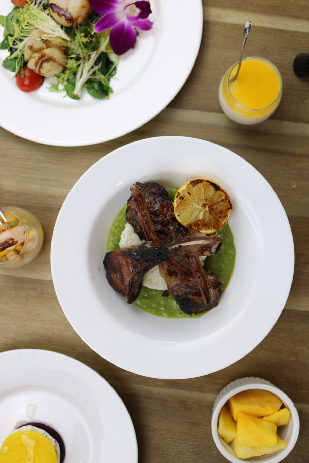 Grilled lamb chops over rice and pea purée, with a scallop salad and mango