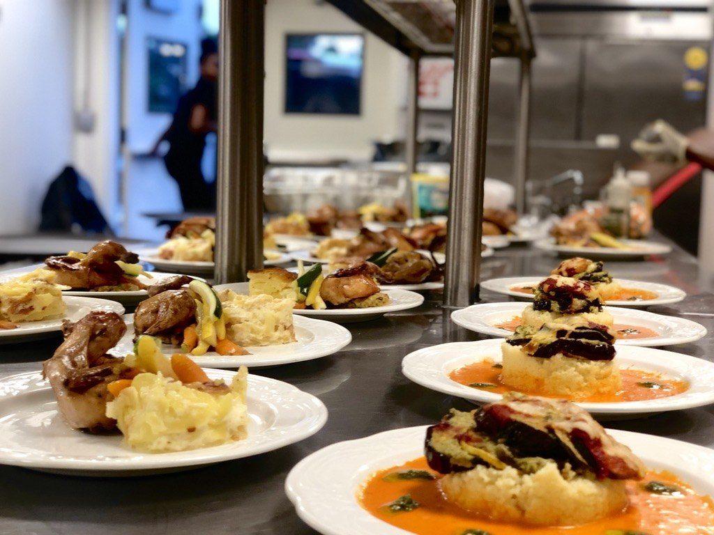 Plated dinners and eggplant stacks lined up at the pass
