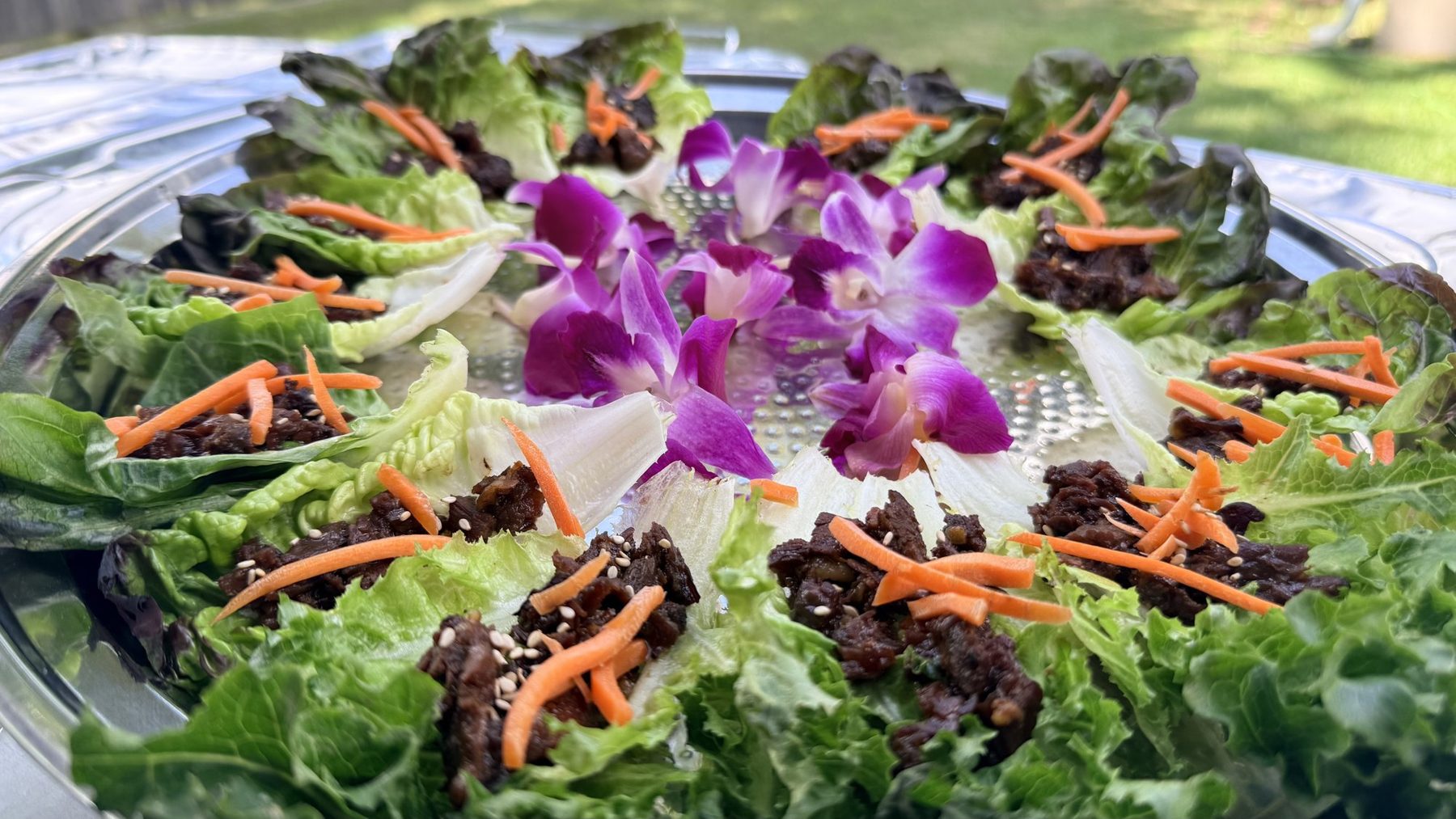 Short rib lettuce wraps on a platter with orchids